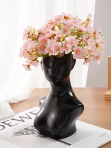 Detailansicht einer schwarzen menschlichen Torsovase aus Harz mit rosa Blumen.
