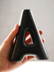 Close-up of a matte black resin A-shape vase being held, highlighting its smooth texture.