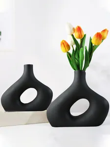 Detail van moderne matzwarte O-vormige vazen met kleurrijke kunsttulpen als decor