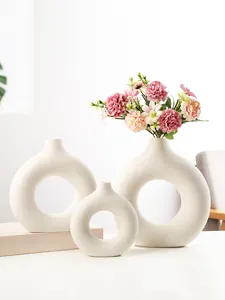 Set van drie witte minimalistische keramische vazen in O-vorm met zijden bloemen