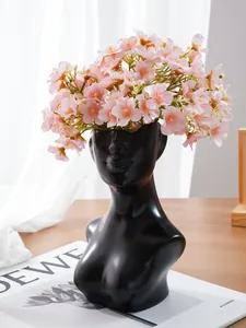 Detailansicht einer kreativen schwarzen Kunstharz-Vase in Menschenform mit rosa Blumen