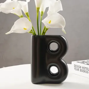 Vaso moderno in resina nera a forma di B con gigli bianchi per l'arredamento della casa