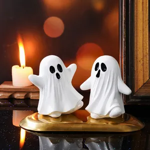 Deux figurines de fantômes d'Halloween en résine sur un plateau doré avec bougie