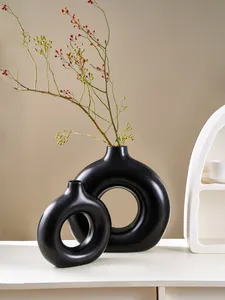 Paar minimalistische zwarte O-vormige keramische vazen met rode bessen voor decor.