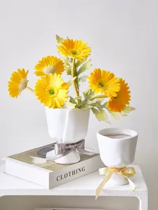 Macro view of white resin flower pots shaped like hand bouquets with elegant ribbons