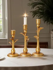 Close-up of three vintage gold palm tree candlesticks with elegant hammered texture