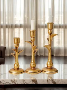 Detailed close-up of three elegant gold palm tree candlesticks set on a marble table