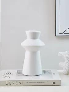 Close-up view of a minimalist white lighthouse-shaped decorative vase on a book