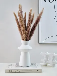 Detail view of a modern white lighthouse-shaped vase with pampas grass