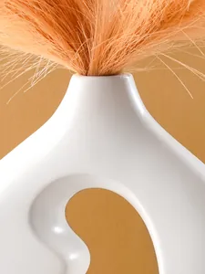 Makroansicht der glatten Oberfläche und des geschwungenen Designs der weißen Keramikvase