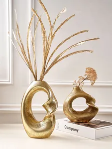 Modern set of two golden abstract resin vases with spiral hollow design for home decor.