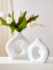Detail von zwei minimalistischen weißen bohnenförmigen Keramikvasen mit Ausschnitten