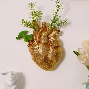 Primer plano de un jarrón de pared creativo con forma de corazón anatómico dorado