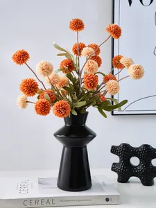 Close-up of a modern black resin lighthouse vase styled with orange artificial flowers