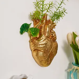 Florero de pared con forma de corazón anatómico dorado y detalles grabados realistas