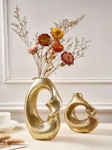 Elegant abstract golden spiral resin vase set with dried flowers in a modern interior
