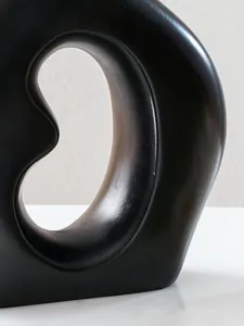 Nahaufnahme einer schwarzen minimalistischen Keramikvase in Bohnenform mit Hohlraum
