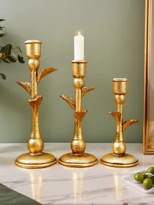 Detail of three golden hammered finish coconut tree candle holders on a marble surface