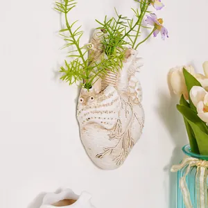 Primer plano de un florero de pared creativo con forma de corazón anatómico con plantas