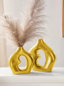 Nahaufnahme eleganter goldener bohnenförmiger Keramikvasen mit dekorativem Pampasgras