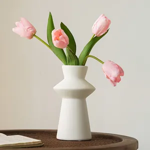 Minimalist Nordic white lighthouse resin vase with artificial pink tulips on a table