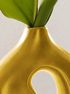 Nahaufnahme einer minimalistischen goldfarbenen Keramikvase in Bohnenform, Detail
