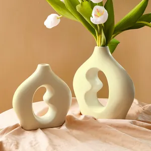 Zwei minimalistische cremefarbene Keramikvasen in Bohnenform mit weißen Tulpen-Deko
