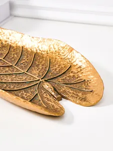 Vue détaillée d'une décoration murale en feuille tropicale or antique montrant la texture