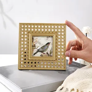 Detail of vintage gold resin photo frame with intricate rattan texture and bird art