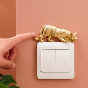 Detail shot of a golden leopard resin figure on a white light switch decor.