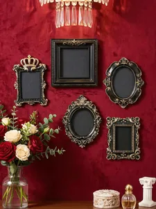 Collection of five mini vintage European black and gold photo frames on a red velvet wall