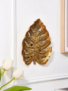 Gros plan d'une sculpture murale en feuille de monstera dorée à texture artistique