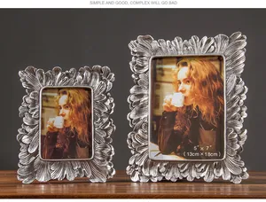 Dos marcos de fotos plateados vintage ornamentados con textura de hojas en madera
