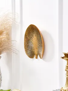 Vue détaillée d'une décoration murale en résine dorée en forme de feuille tropicale