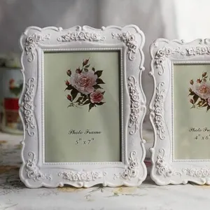 Élégants cadres photo blancs baroques avec roses en relief sur nappe florale