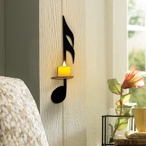 Elegant black iron eighth note wall candle holder shown with a warm lit candle detail