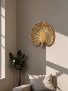Détail d'une décoration murale en résine dorée en forme de feuille tropicale dans un salon.