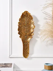 Vue détaillée d'une décoration murale feuille tropicale dorée avec texture martelée