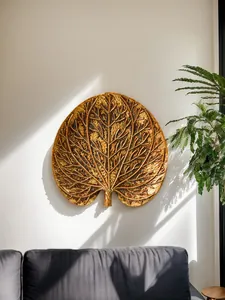 Détail de la décoration murale en résine de feuille tropicale dorée dans un intérieur.