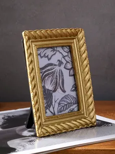 Nahaufnahme eines goldenen Vintage-Rahmens mit Spiralmuster auf einem dunklen Holztisch