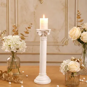 Primer plano de un portavelas de columna romana blanca con vela y decoración floral de boda