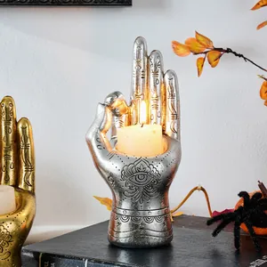 Macro detail of silver hand candle holder with mystical eye and palmistry symbols.