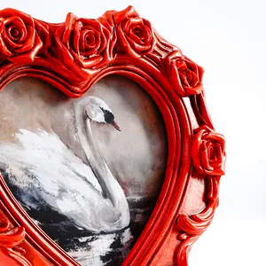 Nahaufnahme des alten roten herzförmigen Fotorahmens mit aufwändigen Rosenschnitzereien.