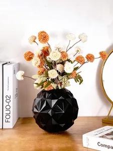 Detailopname van zwarte geometrische vaas met modern ruitpatroon en droogbloemen.