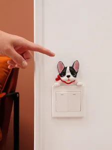 Cute resin French Bulldog figurine decorates a white light switch on a textured wall