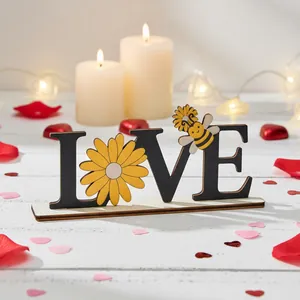 Close-up detail of wooden LOVE ornament featuring a yellow daisy and cartoon bee