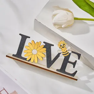 Detail view of a handcrafted wooden LOVE ornament featuring a yellow daisy and bee