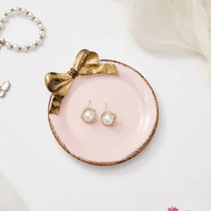 Detalle de bandeja de joyas rosa con lazo dorado y pendientes