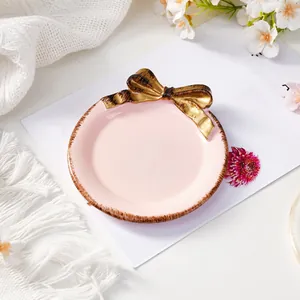 Vista detallada de una elegante bandeja para joyas rosa con lazo dorado vintage