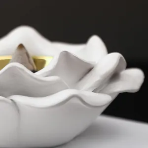Primer plano de un quemador de incienso de flujo inverso de cerámica blanca con forma de rosa.